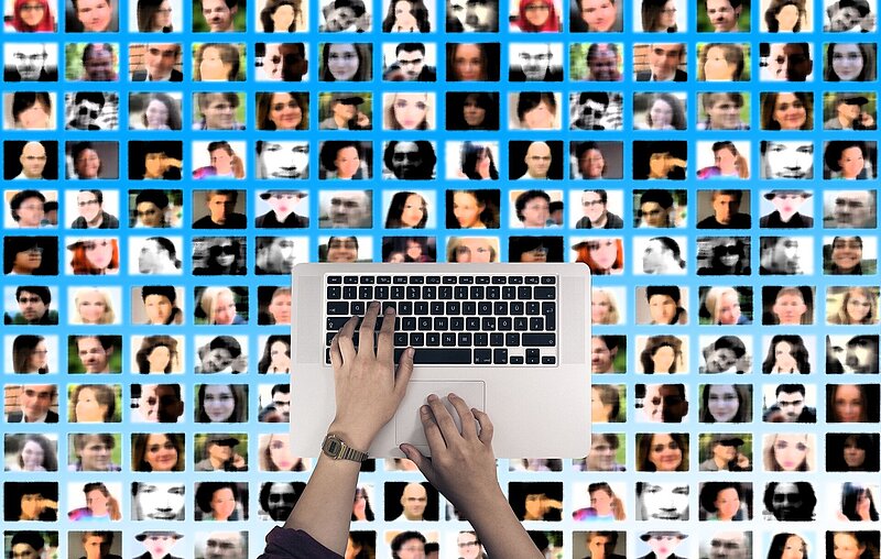 Ein Raster aus kleinen unscharfen Profilbildern im Hintergrund, davor eine Tastatur mit zwei Händen