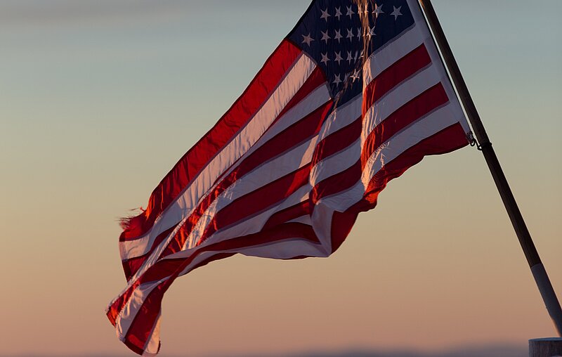 Die US-amerikanische Flagge vor einem Horizont bei Dämmerung