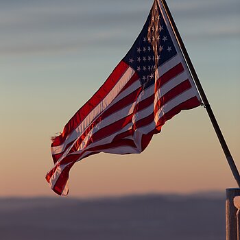 Die US-amerikanische Flagge vor einem Horizont bei Dämmerung