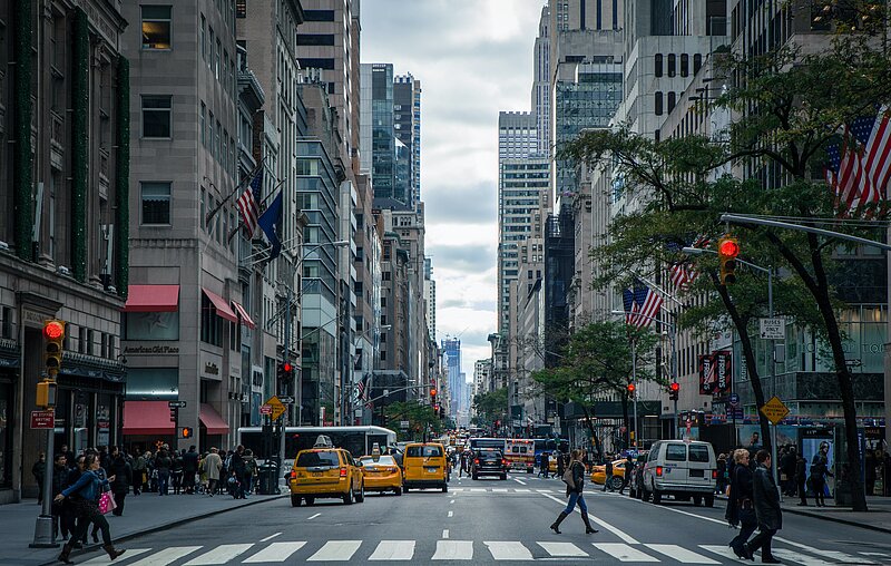 Straßenschlucht in New York mit gelben Taxis und vielen Menschen