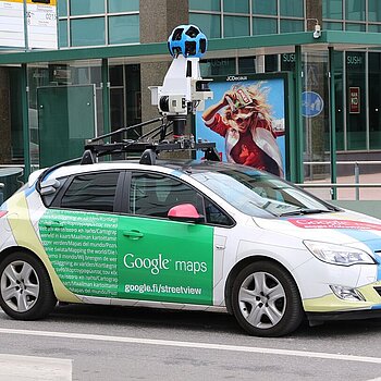 Ein Google-Maps-Auto mit Rundumkamera auf dem Dach fahrt durch eine Straße