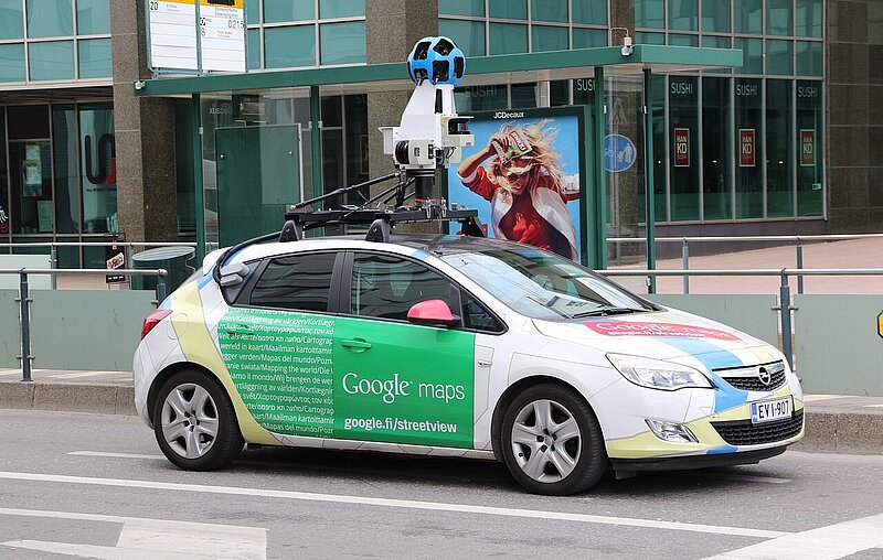 Ein Google-Maps-Auto mit Rundumkamera auf dem Dach fahrt durch eine Straße