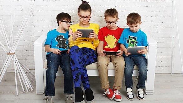 Vier Kinder schauen ihr Smartphone